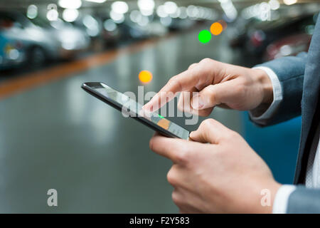 Parking en location un homme à l'aide de son téléphone cellulaire. Close-up hands Banque D'Images