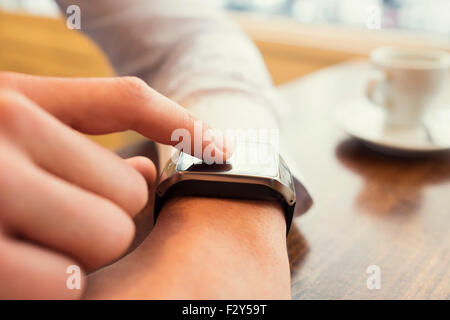 L'homme dans un bar à l'aide de smart watch. Close-up du doigt. Filtre Vintage Banque D'Images