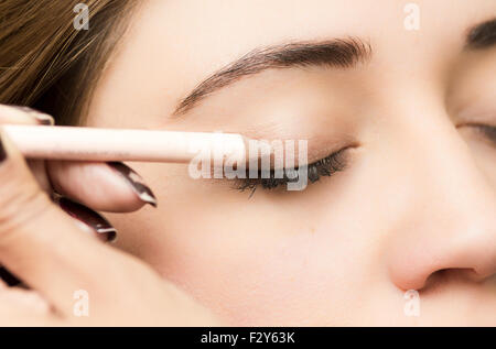 Closeup portrait brune s traitement maquillage styliste professionnel par l'application de l'eyeliner Banque D'Images