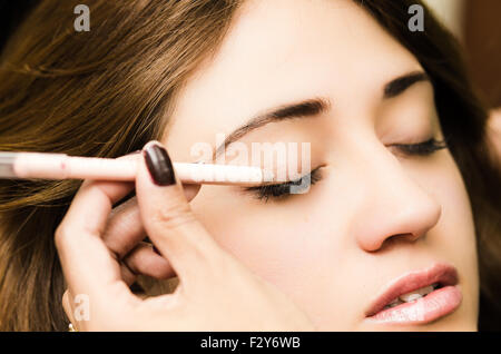 Closeup portrait brune s traitement maquillage styliste professionnel par l'application de l'eyeliner Banque D'Images