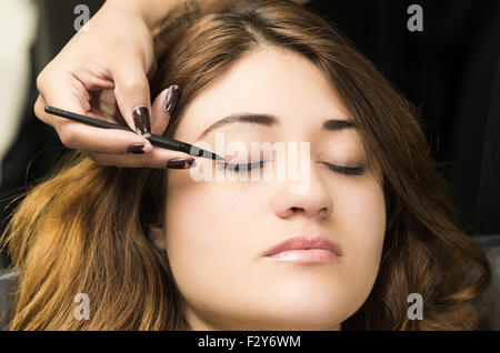 Closeup portrait brune s traitement maquillage styliste professionnel par l'application de l'eyeliner Banque D'Images