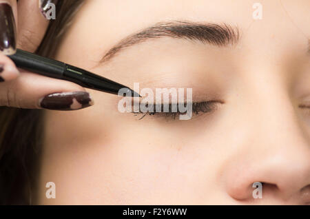 Closeup portrait brune s traitement maquillage styliste professionnel par l'application de l'eyeliner Banque D'Images