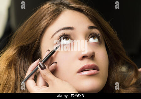 Closeup portrait brune s traitement maquillage styliste professionnel par l'application de l'eyeliner Banque D'Images