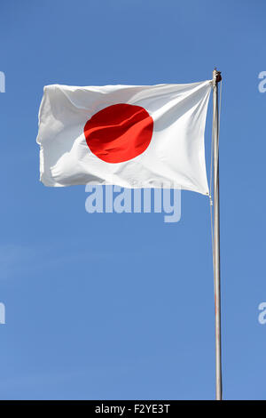 Drapeau japonais en vent contre ciel bleu clair Banque D'Images