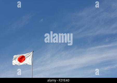 Drapeau japonais en vent contre ciel bleu clair Banque D'Images