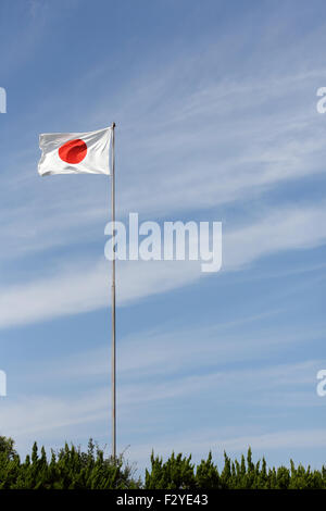 Drapeau japonais en vent contre un ciel bleu Banque D'Images