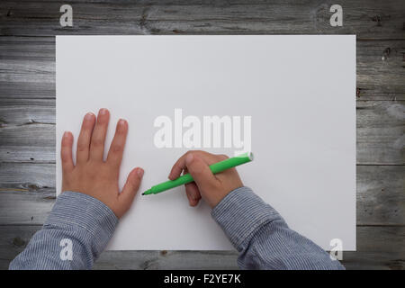 Enfant tenant plume sur feuille de papier vierge Banque D'Images