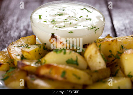 La sauce à l'ail dans un bol et quelques pommes de terre adossés à des problèmes de mise au point Banque D'Images