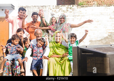 Groupe indien foule villageois rural famille mixte home sitting Charpai et regarder la télévision Banque D'Images