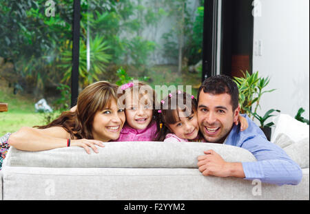 Belle hispanique famille de quatre personnes qui posent avec les chefs qui le retour du canapé à la caméra en souriant Banque D'Images