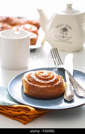 Kanelbullar suédois, brioches à la cannelle et une tasse de thé sur une table Banque D'Images