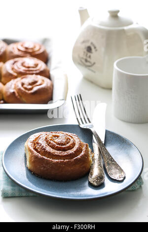 Kanelbullar suédois, brioches à la cannelle et une tasse de thé sur une table Banque D'Images