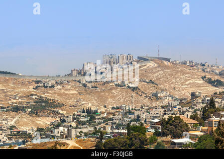 Village palestinien et la ville sur la colline derrière un mur de séparation en Cisjordanie, en Israël. Banque D'Images