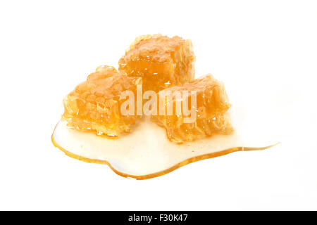 Trois cubes en nid d/ pièces en sirop dégoulinant de miel à base de produits frais du miel bio de thym sauvage grecque dentelle sur fond blanc. Banque D'Images