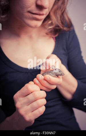 Une jeune femme tient sa minuscule souris pet Banque D'Images