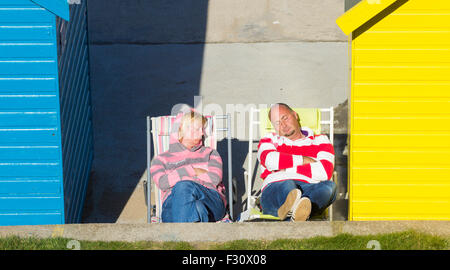 L'homme et de la femme de dormir sur des chaises longues au soleil à l'extérieur de cabane de plage, à Whitby, North Yorkshire, UK. Banque D'Images