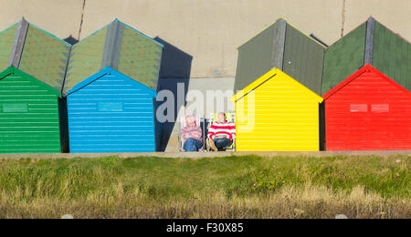 Dimanche 27 septembre 2015, Whitby, North Yorkshire, Angleterre, Royaume-Uni. Météo : sieste au soleil près de cabanes de plage sur un glorieux dimanche à Whitby, North Yorkshire. Banque D'Images