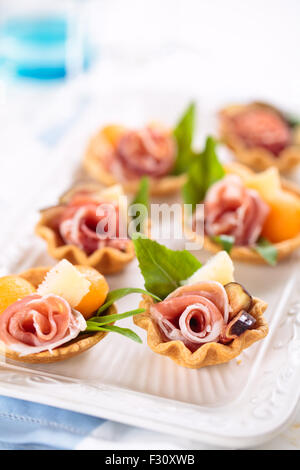 Tartelettes à la viande, basilic, boules de melon et de figue. Banque D'Images