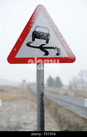 A road sign covered in snow warning car drivers of hazardous driving conditions. Banque D'Images
