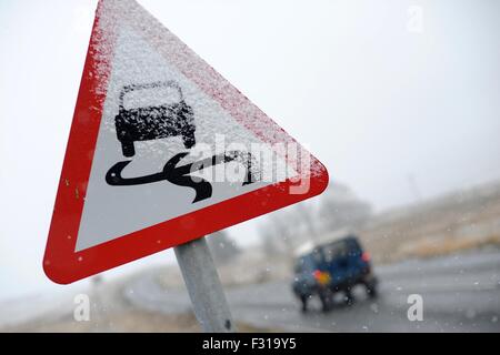 Un panneau routier couvert de neige les conducteurs de voiture avertissement de conditions routières dangereuses. Banque D'Images