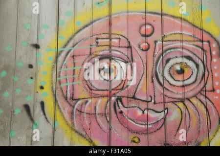 Détail de l'art de la rue Graffitis Coloré d'un visage ensoleillé souriant peint sur une vitre d'obturation par l'artiste connu sous le nom de Loko. Montpellier, Sud De La France. Banque D'Images