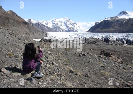 Jeune fille en prenant une photo de la fonte des glaciers de l'arm, Hvannadalshnúkur Öraefajökull volcan en Islande. Banque D'Images