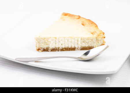 Coin de gâteau au fromage avec cuillère à café on white plate Banque D'Images