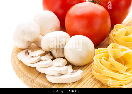 Spaghettis et pâtes nids avec des champignons et de la direction générale des tomates sur planche à découper en bois Banque D'Images