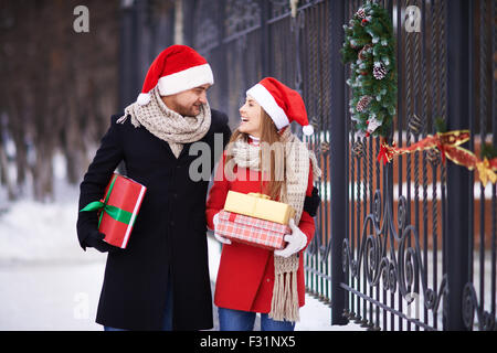 Friends à Santa caps et les manteaux à la maison avec des cadeaux pour Noël Banque D'Images