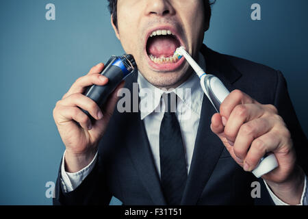 Un homme d'affaires est en retard et a souligné est le rasage et le brossage des dents en même temps Banque D'Images