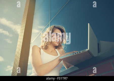 Belle étudiante travaillant avec un ordinateur portable à côté de la bibliothèque. l'extérieur brickwall Banque D'Images