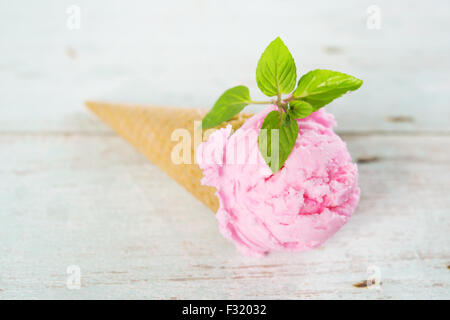 Glace à la rose en cornet gaufré sur fond de bois vintage rustique ancien. Banque D'Images