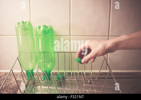 Gros plan sur la main d'une jeune femme comme elle est de lavage et de recyclage des bouteilles en plastique Banque D'Images