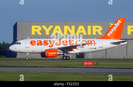 Avion EasyJet G-EZAK, Airbus A319-111 passe le hangar par Ryanair la piste à l'aéroport de Stansted Banque D'Images