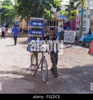 Man wheeling location chargement de Pepsi sur dirt street , Mto Wa Mbu, Tanzanie. Ce village est sur la route principale d'Arusha de Serengeti. Banque D'Images