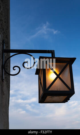 Ancienne lampe de rue monté sur mur de pierre sur fond de ciel bleu foncé Banque D'Images