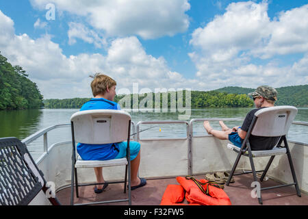 Deux jeunes garçons assis sur des chaises sur le pont d'un bateau dans un lac dans l'Alabama Banque D'Images