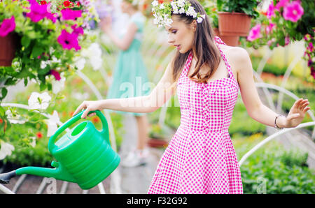 Gorgeous woman arroser les fleurs Banque D'Images