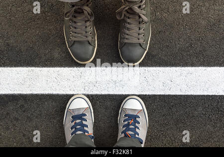 Pieds de sneakers, debout à côté de la rue Blanche. Profondeur de champ Banque D'Images