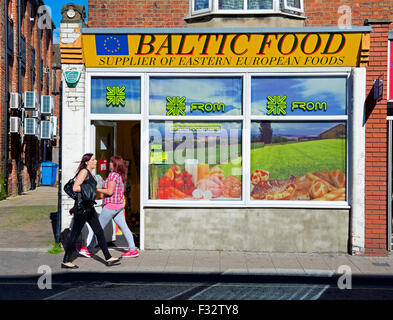 Deux jeunes femmes marchant passé boutique de produits alimentaires d'Europe de l'est à Boston, Lincolnshire, Angleterre, Royaume-Uni Banque D'Images