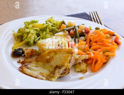 Dans l'image d'un filet de poisson frit avec légumes servi sur plat blanc au restaurant. Banque D'Images