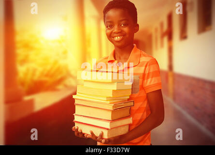 Image composite de portrait of cute boy carrying books in library Banque D'Images