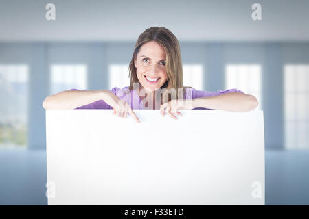 Image composite de portrait of smiling businesswoman pointing at blank billboard Banque D'Images