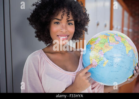 Composite image of woman pointing to globe Banque D'Images