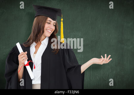 Image composite d'une femme tenant sa main avec un degré dans son autre main, elle sourit Banque D'Images
