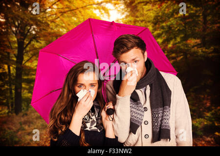 Image composite du couple blowing nose alors que holding umbrella Banque D'Images