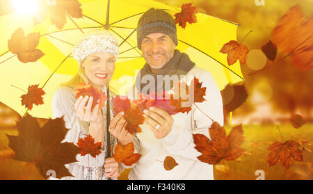 Image composite de portrait de couple holding autumn leaves en position debout sous parapluie jaune Banque D'Images