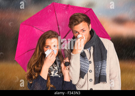 Image composite du couple blowing nose alors que holding umbrella Banque D'Images