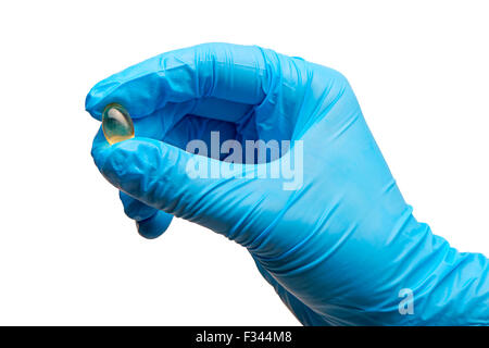 Close up de la main du médecin en bleu les gants chirurgicaux stérilisés holding comprimé jaune contre fond blanc Banque D'Images