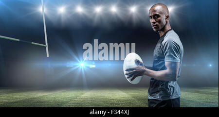 Image composite de portrait of permanent de l'athlète avec ballon de rugby Banque D'Images